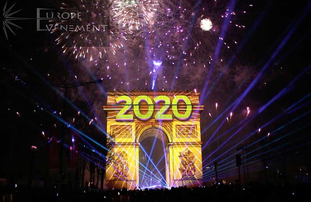 Photo of the Arc de Triomphe illuminated at night with the year 2020 projected on it and fireworks around