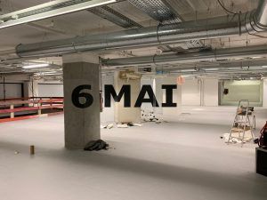Photo of an anamorphosis writing May 6 on the posts of an underground car park