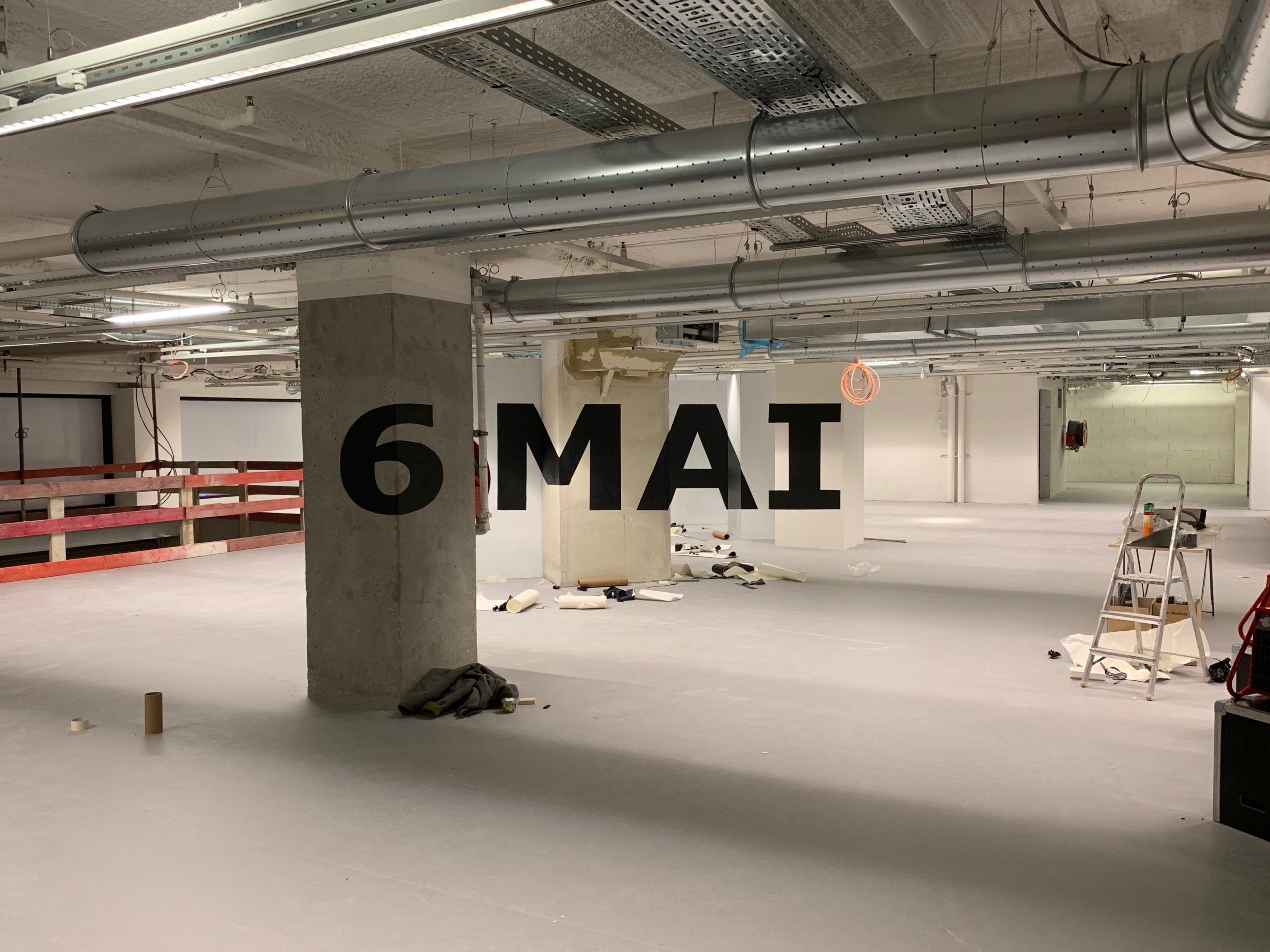 Photo of an anamorphosis writing May 6 on the posts of an underground car park