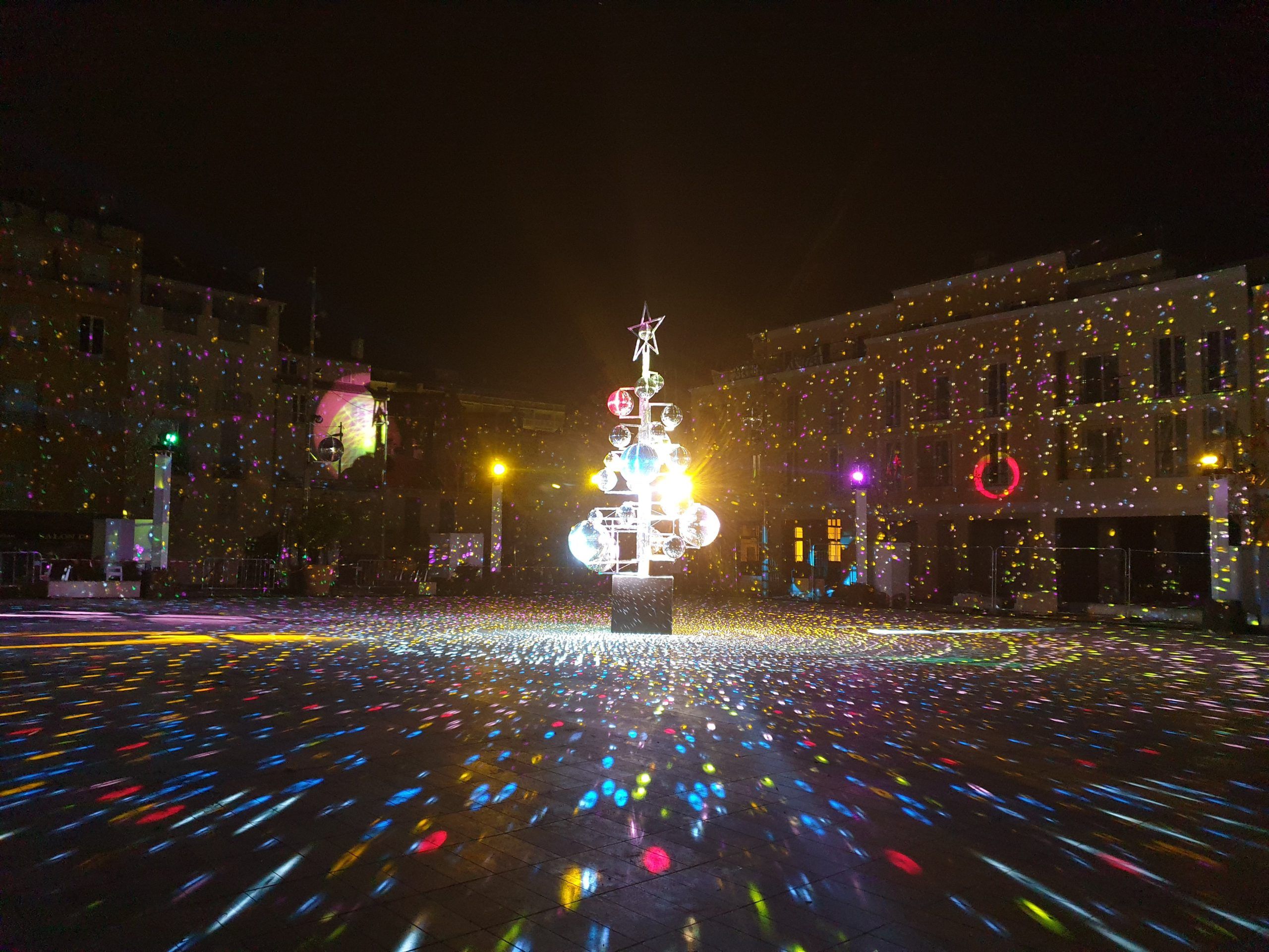 Europe Évènement - Photo of a town square with tree in the center illuminating the ground with multiple colors in Antibes