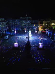 Photo of a town square with a disco ball tree in the center and white, blue and green lights