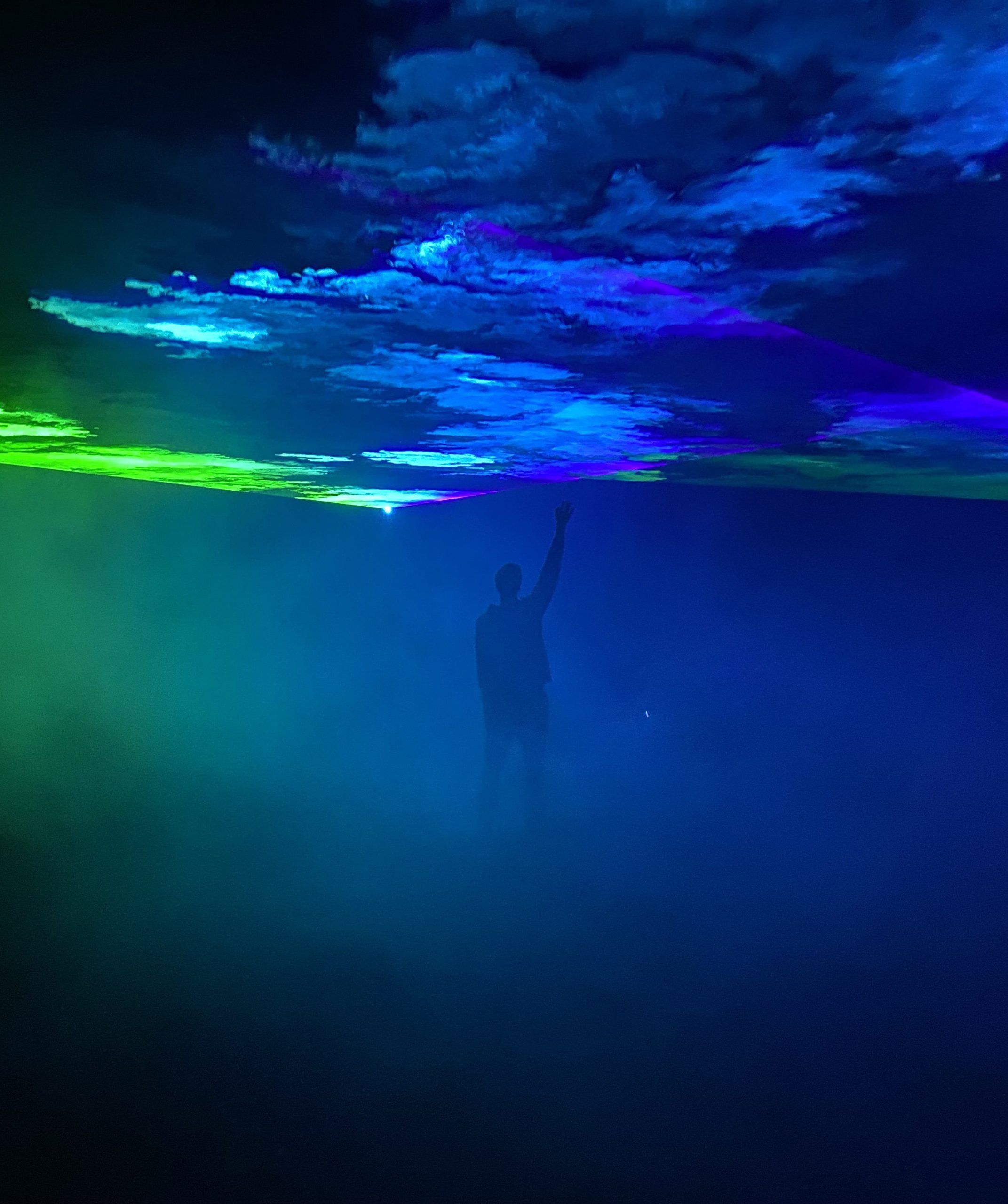 Photo of a man raising his hand to touch blue and green smoke splash