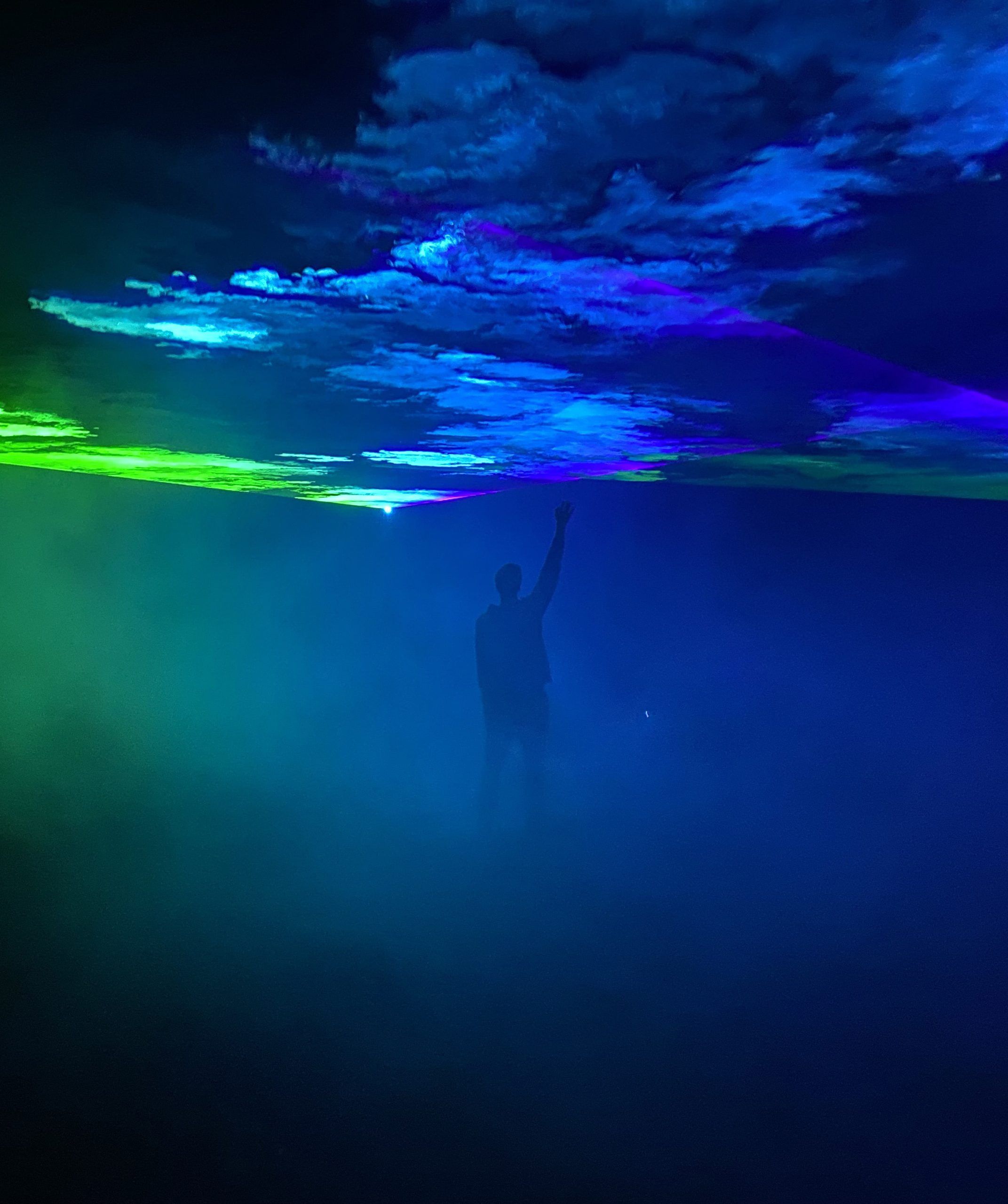Aurora Borealis - Photo of a man raising his hand to touch blue and green smoke splash