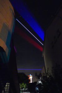Photo of blue and red lasers projected above buildings