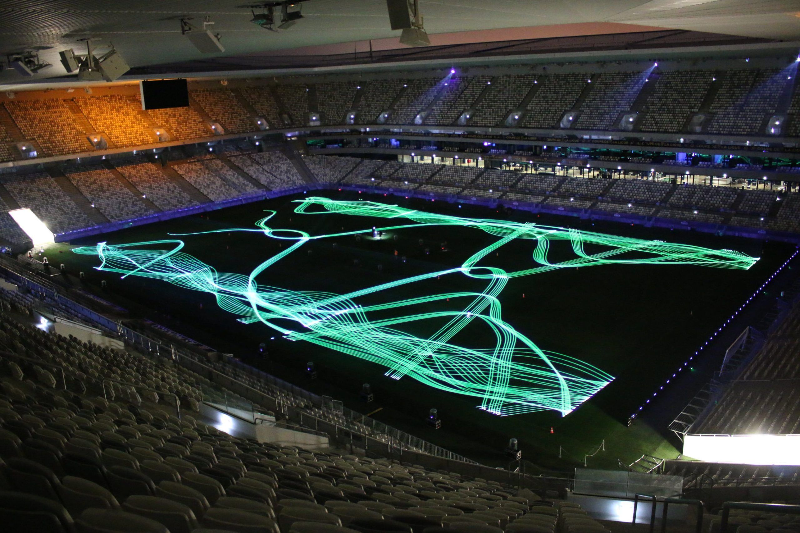 Photo of a stadium with projection of green laser shapes on it