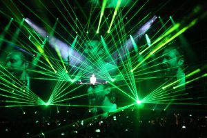 Photo of a DJ David Guetta concert with green laser beams around him