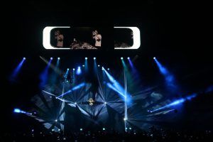 Photo of a concert by DJ David Guetta with laser beams and blue lights around him
