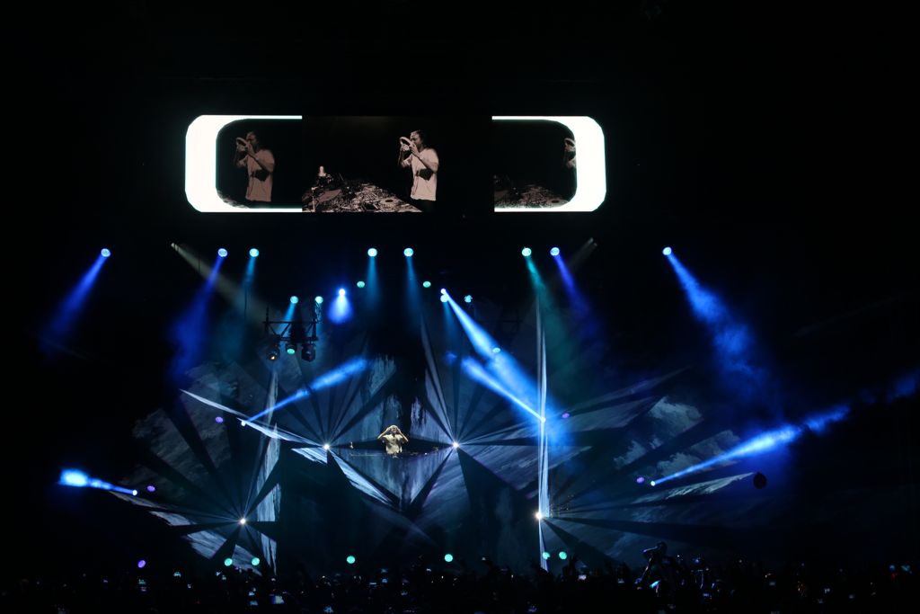Photo of a concert by DJ David Guetta with laser beams and blue lights around him