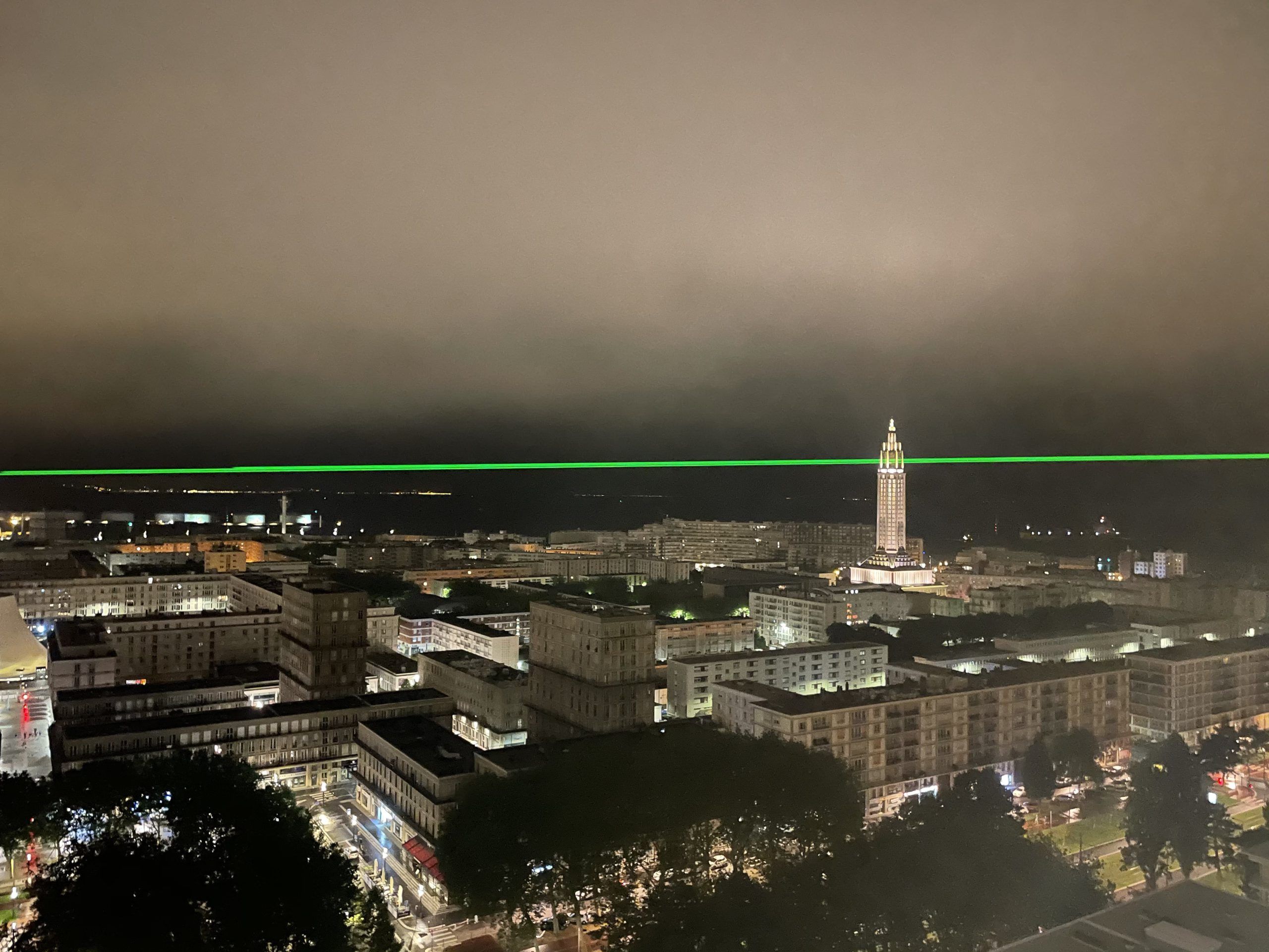 Photo of a green laser beam projected into the sky