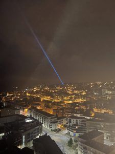 Photo of a blue laser beam shot skyward over a city