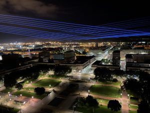 Photo of a city with blue laser beams passing overhead