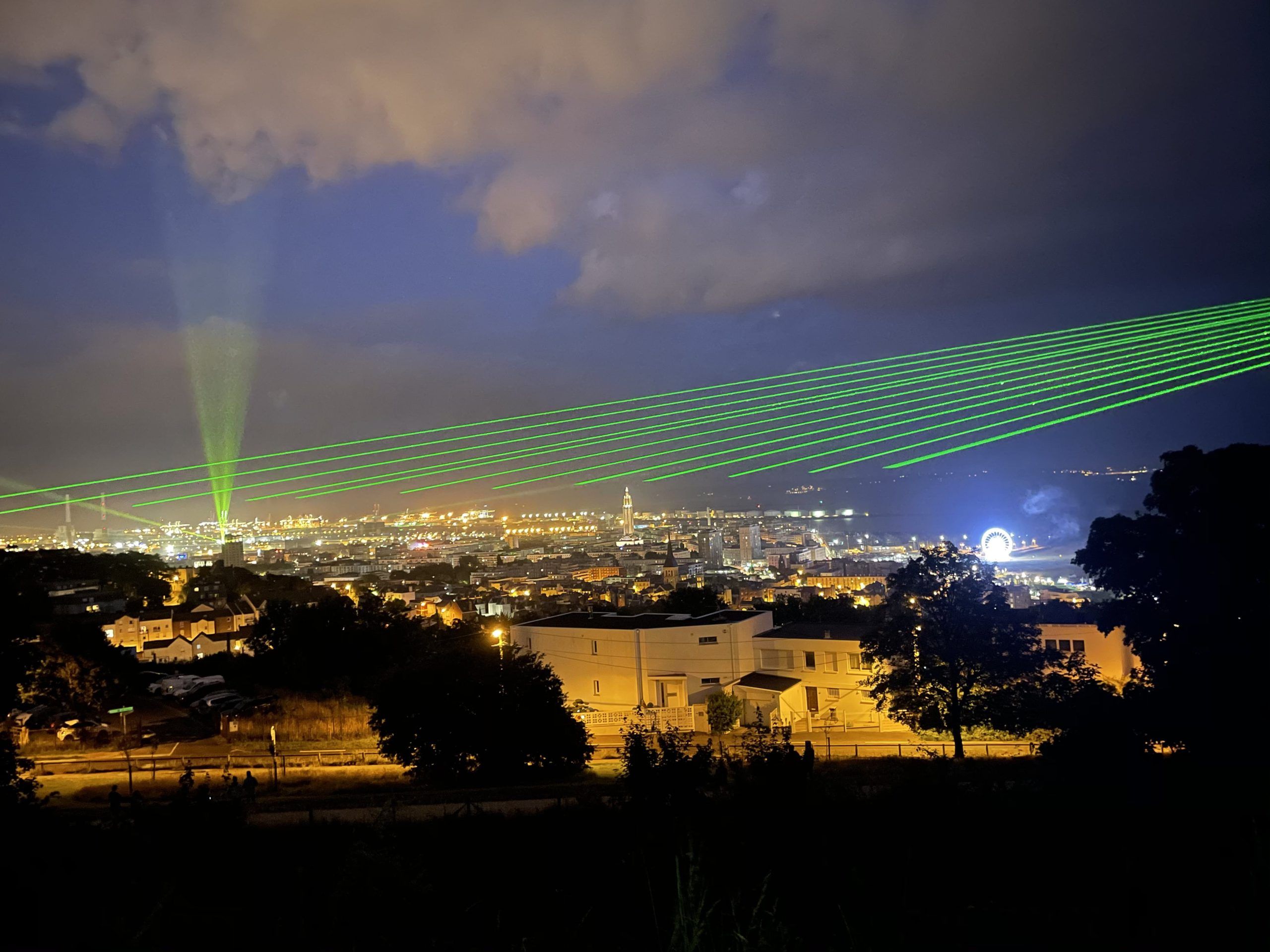 Photo of green laser beams projected above a city