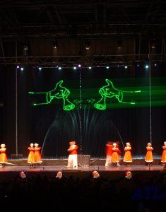 Photo of people dancing with fountains and christmas illustration projection on water screen