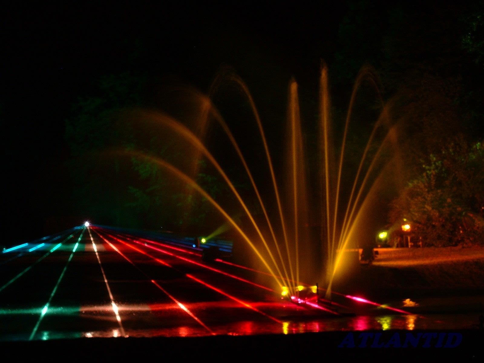 Photo of blue, green and red laser beams with orange fountain jets
