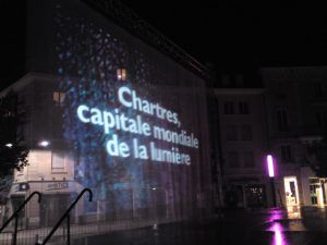 Photo of a curtain of water with the text Chartres, world capital of light projected on it
