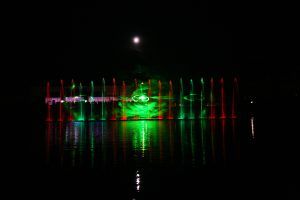 Photo of red and green fountain jets with smoke and laser green spiral projection