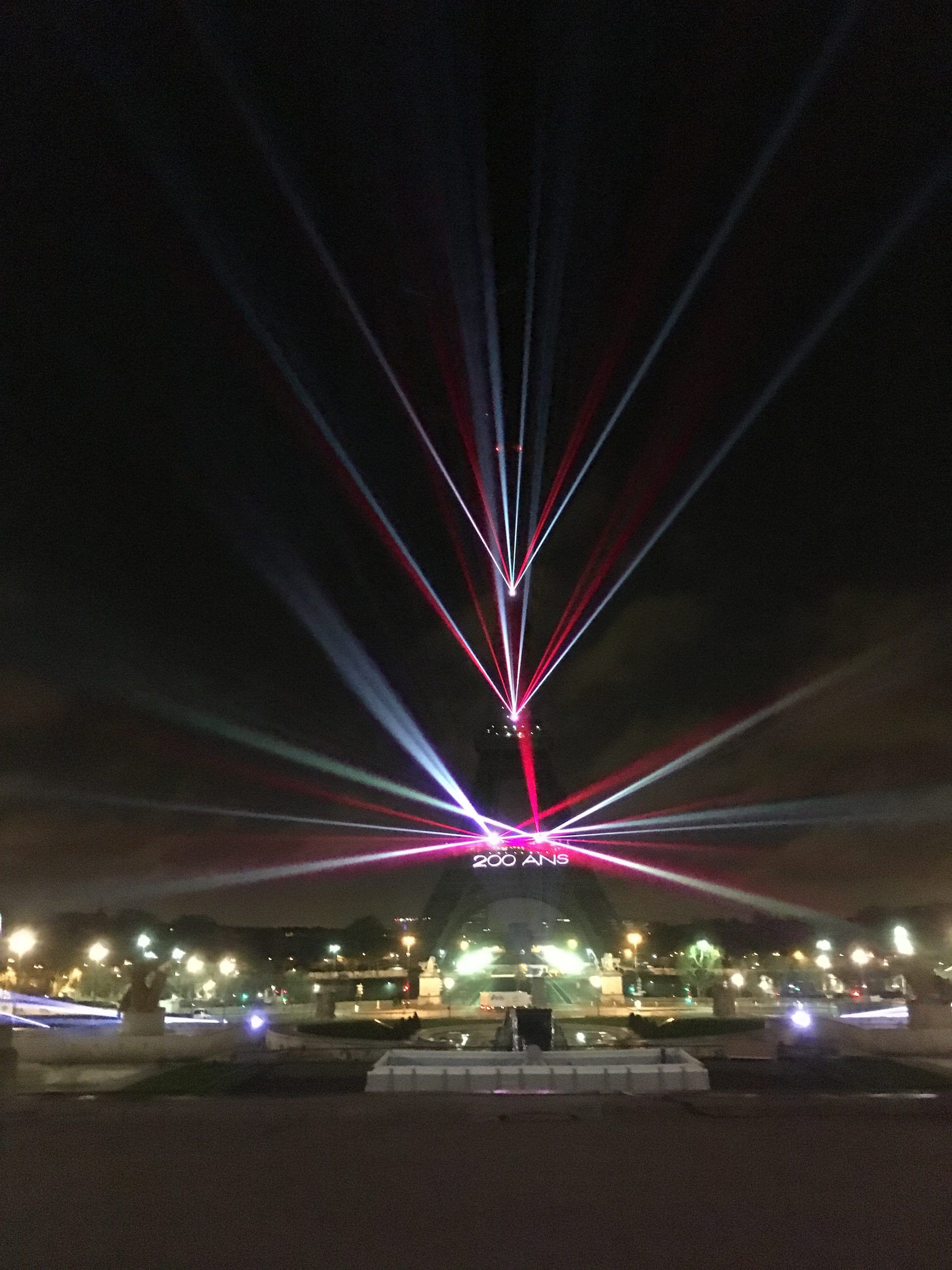 Photo of the Eiffel Tower with 200 years written on it and red and white laser beams
