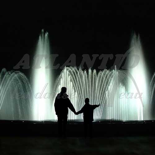 Europe Évènement - Photo of a fountain with white jets of water and the shadows of a man holding a child's hand in front