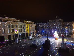 Photo of a town square with a disco ball tree in the center and lasers projecting on it