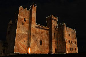 Photo of a castle with projection of geometric shapes above and flames