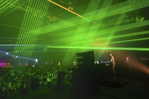 Photo of a concert with green laser beams crossing the room