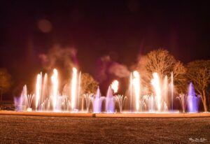 Photo of flames aligned with white and purple jets of water