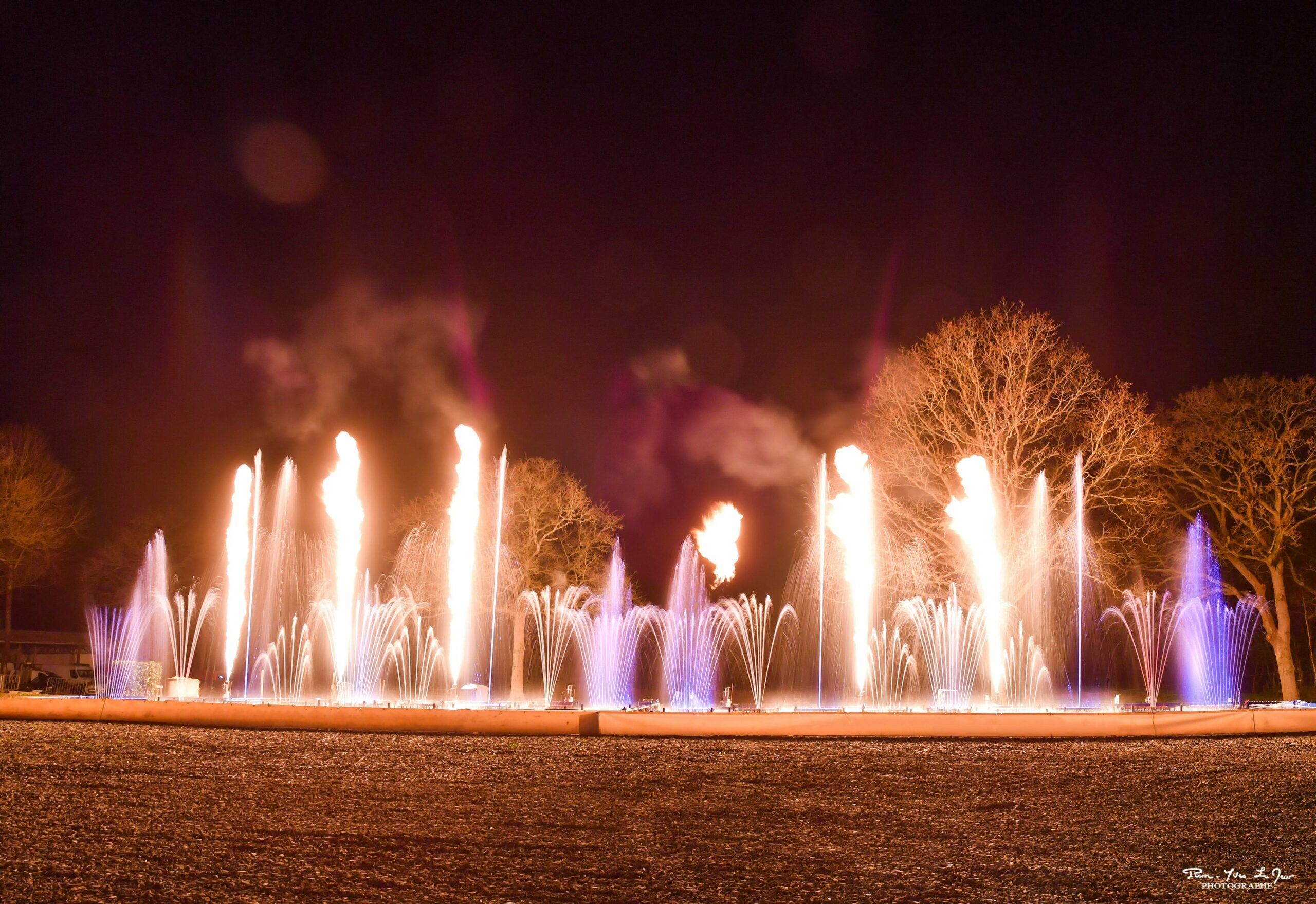 Europe Évènement - Photo of flames aligned with white and purple jets of water