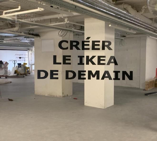 Europe Évènement - Photo d'une anamorphose écrivant Créer le Ikea de demain sur les poteaux d'un parking souterrain