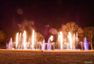 Europe Évènement - Photo de flammes alignées avec des jets d'eau blancs et violets