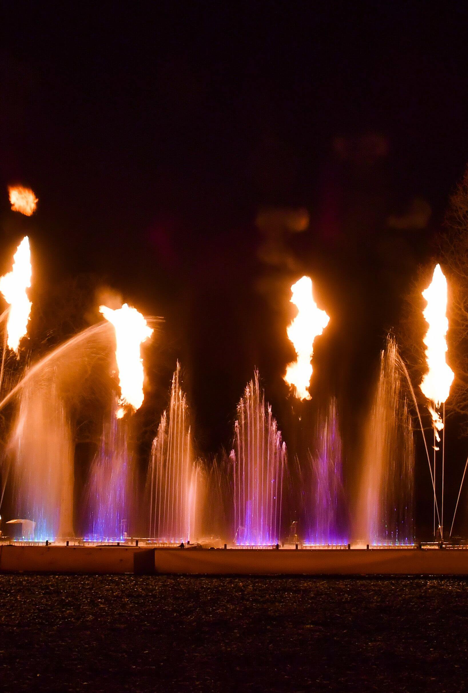 Europe Évènement - Photo de flammes avec des jets d'eau de couleur violet derrière