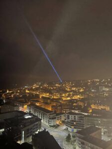 Europe Évènement - Photo d'un faisceau laser bleu projeté vers le ciel au-dessus d'une ville au Havre