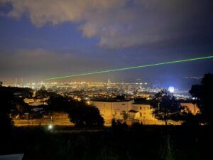 Europe Évènement - Photo d'un faisceau laser vert projeté dans le ciel d'une ville