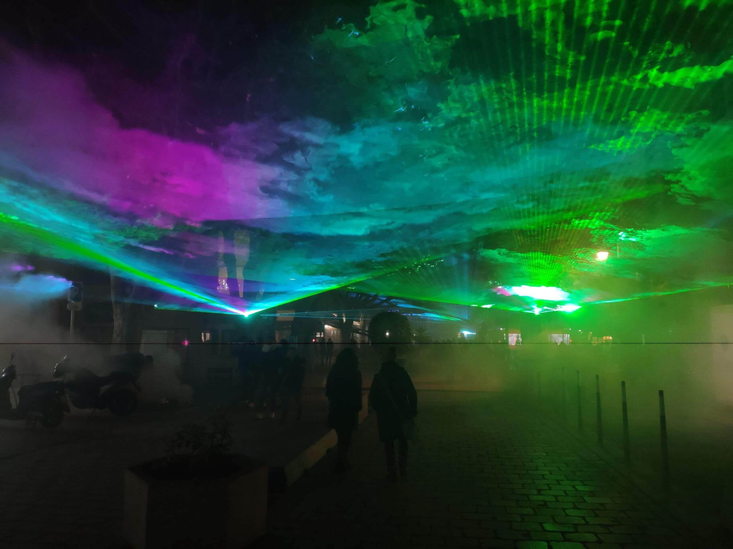 Europe Évènement - Spectacle laser - Photo d'un centre ville avec une aurore boréale de couleurs bleu, vert et rose dans le ciel