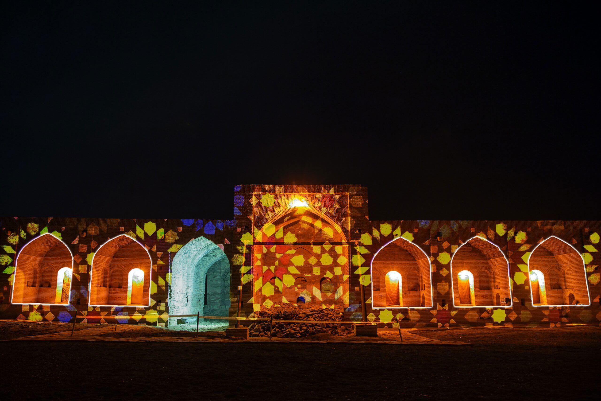Europe Évènement - Photo of a caravanserai with mosaic shapes projected onto it and the outlines of the openings traced.
